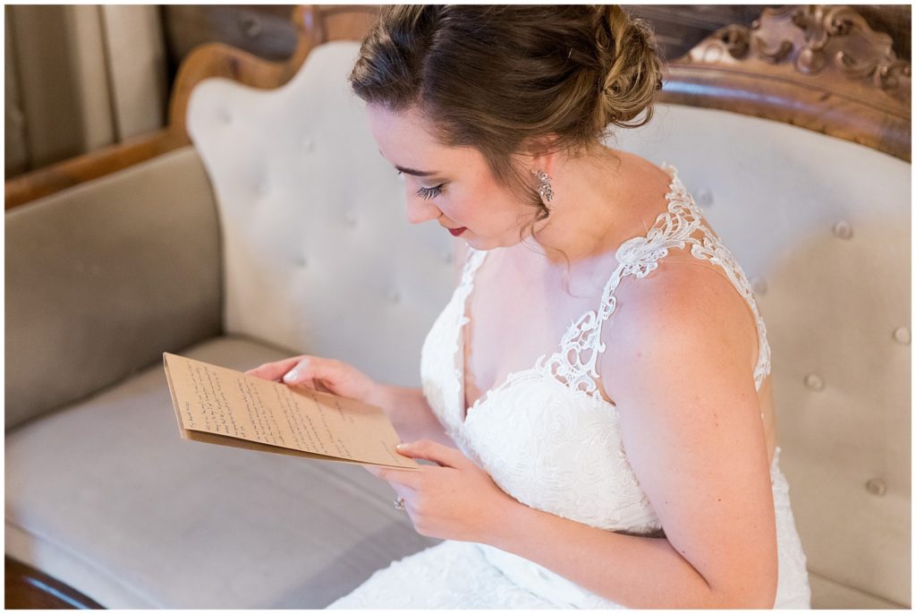 Bride reading letter from groom indoors on antique couch