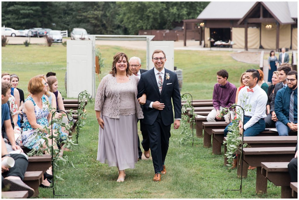 Soon to be groom and mother walk down outdoor aisle
