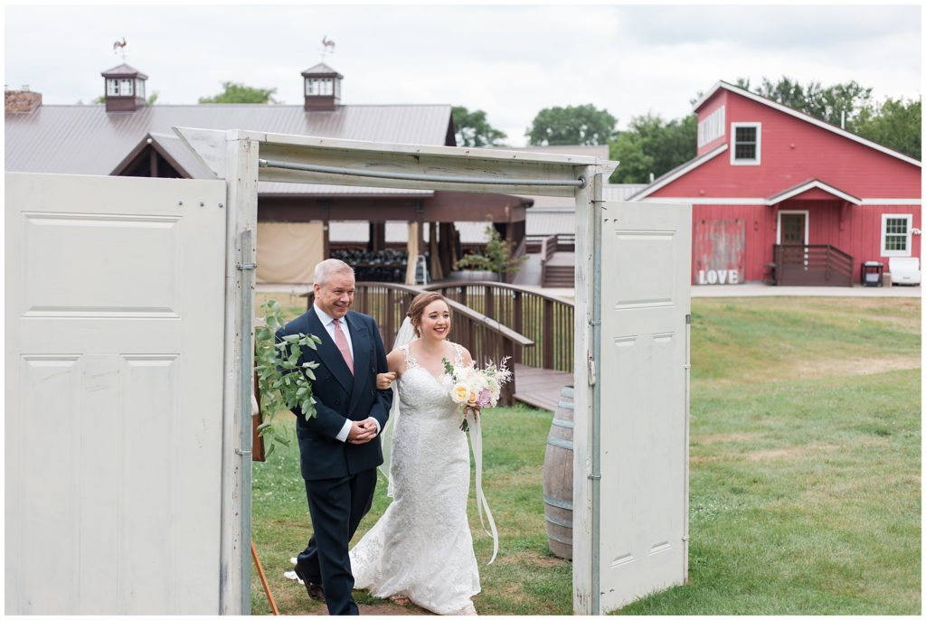 Soon to be bride and father walk through outdoor doorway to aisle at Hope Glen Farm
