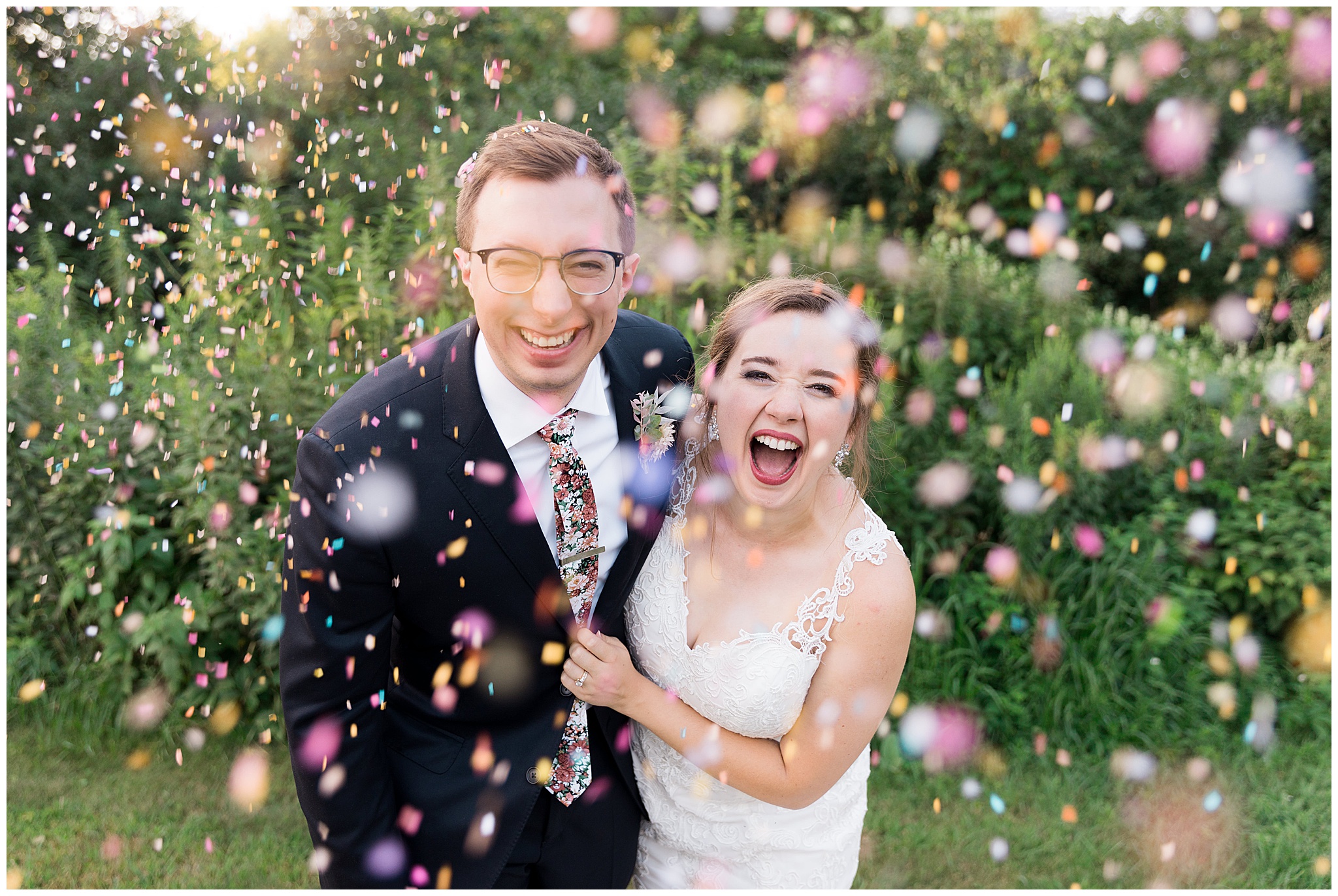 wedding couple laughs as confetti falls in front of them at Hope Glen Farm near Minneapolis Minnesota