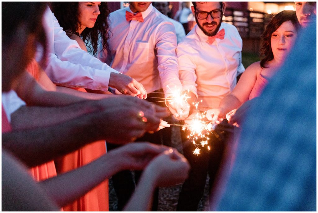 Wedding party and guests light sparklers outside for sparkler exit