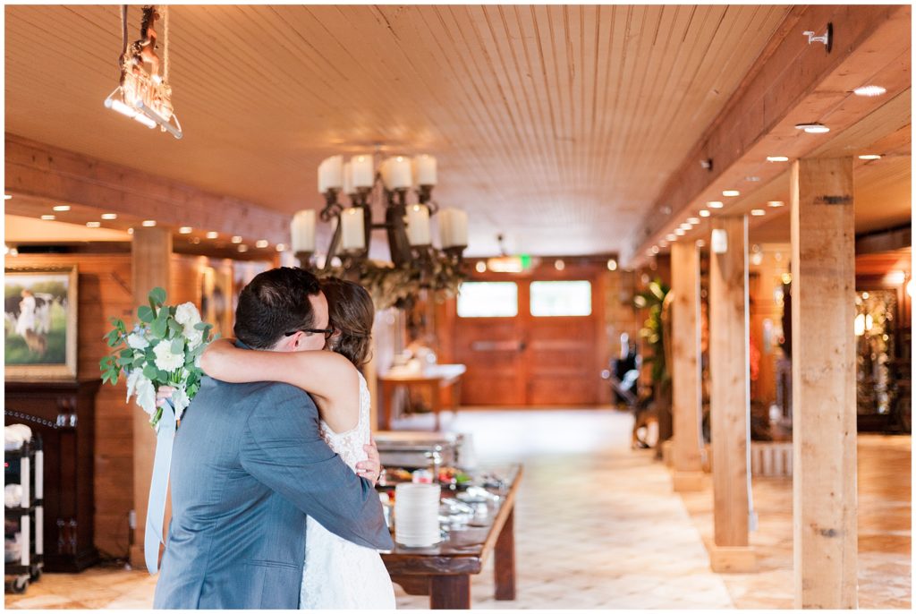 Bride and groom taking a private moment to hug after wedding ceremony indoors in reception space.