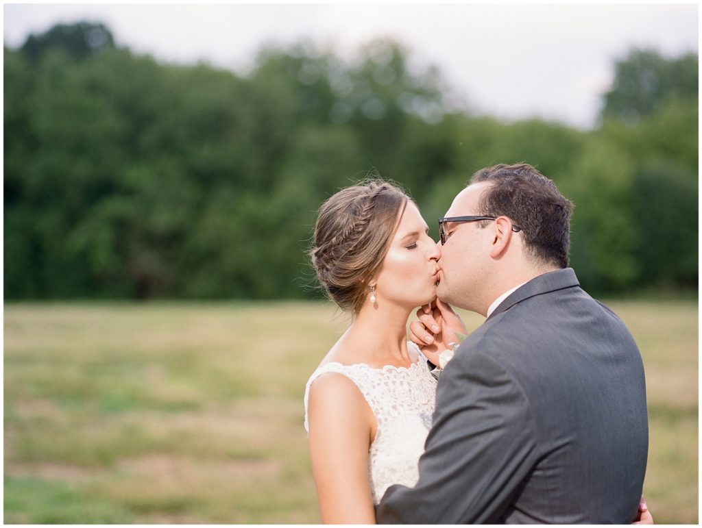Golden hour photograph of newly married couple kissing outside at Green Acres Event Center