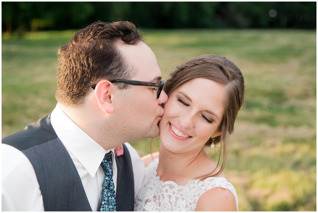 Closeup photograph of just married couple, groom kissing bride's cheek at Green Acres Event Center