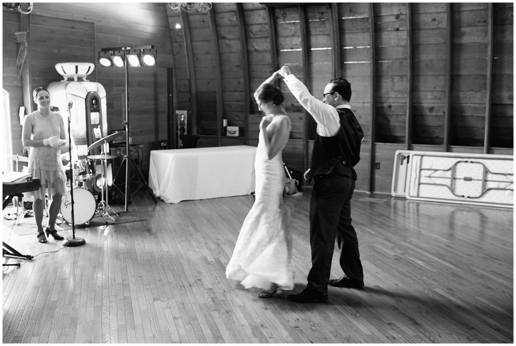 Black and white photograph of just married couple swing dancing during indoor wedding reception in Minnesota.