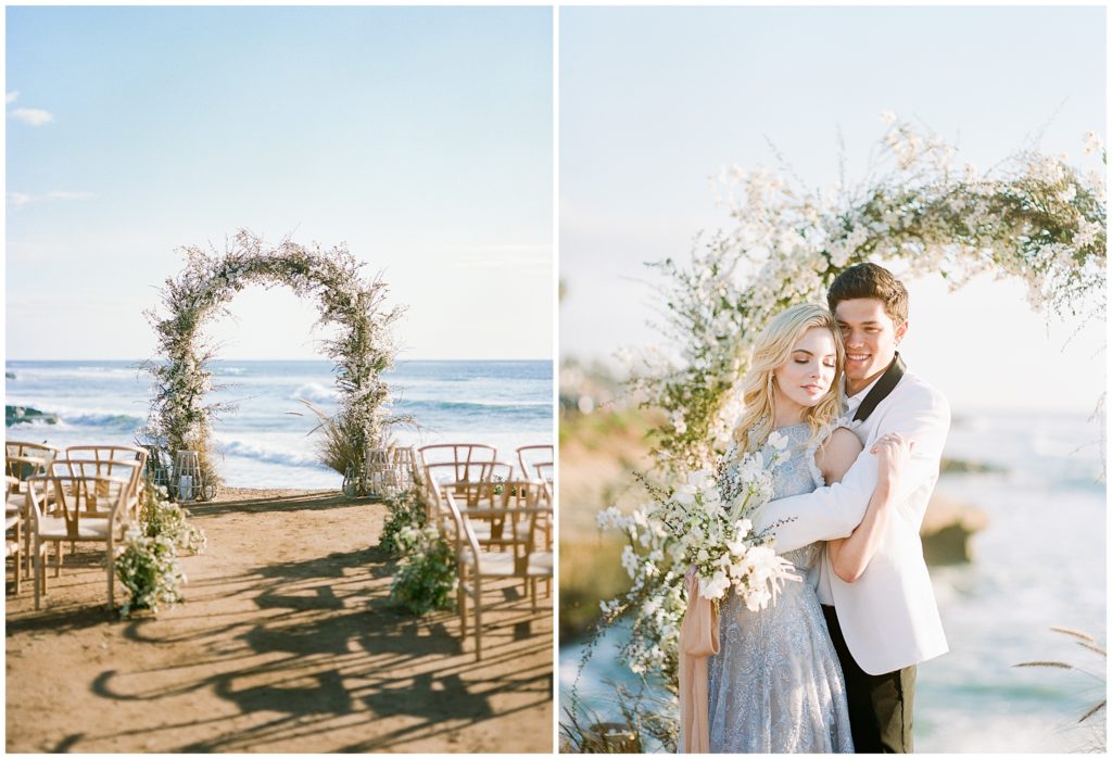A green and white archway set on the beach in front of wooden chairs for a small, intimate beach wedding. Models Katherine Neff and David Grinsfelder embrace in front of the archway at sunset at the Pacific Ocean