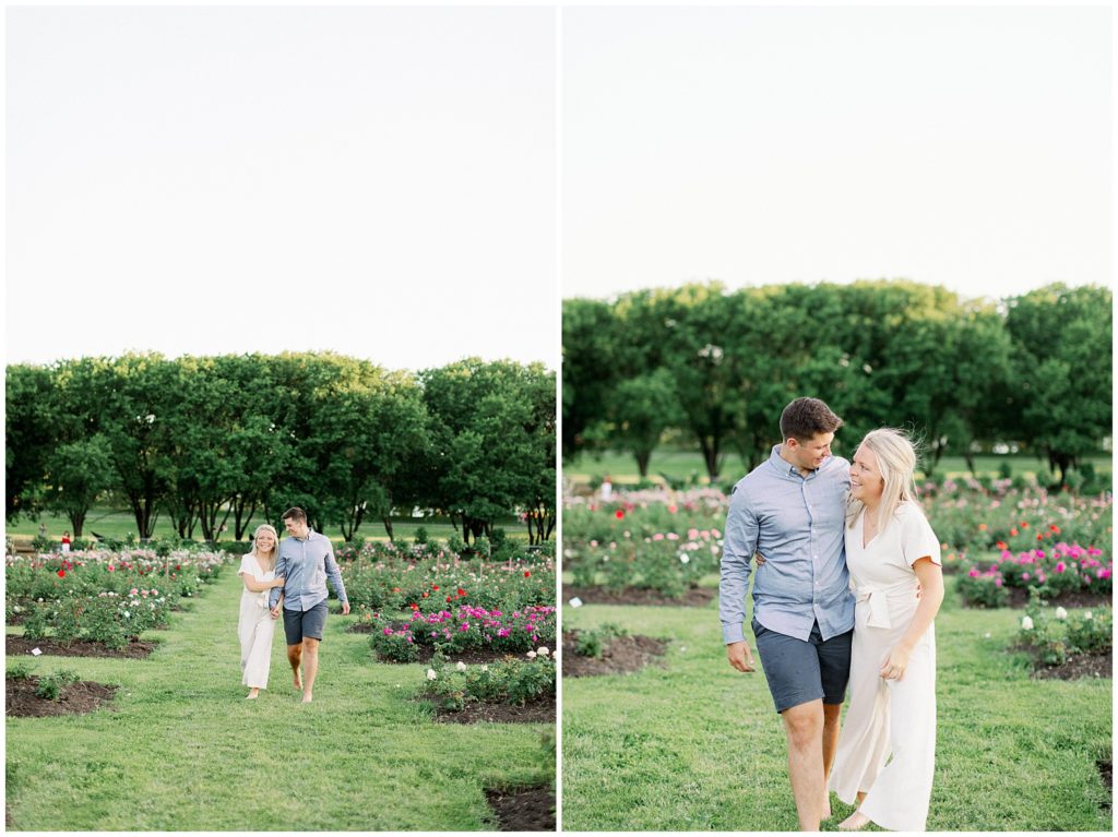 Boyfriend and girlfriend laugh and walk along rows of roses in a Minneapolis garden