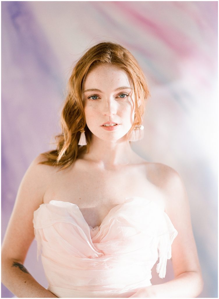 Fine art colorful portrait, featuring bride wear Claire LaFaye pink gown in front of purple and pink background