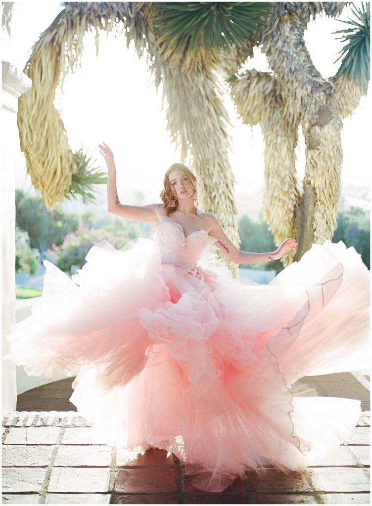 Spring wedding inspiration featuring bride showing off her beautiful, flowing pink wedding gown by Claire LaFaye during destination wedding in San Diego.
