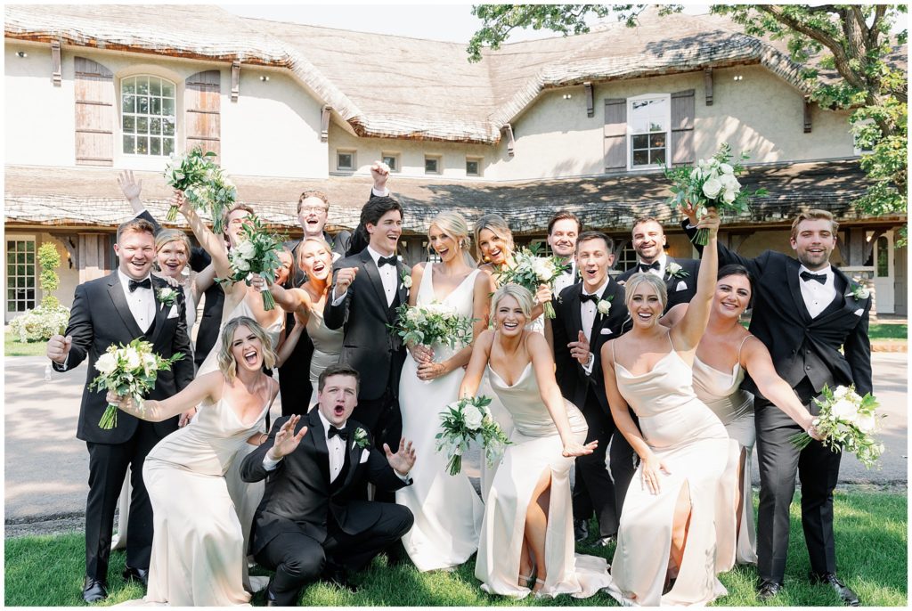 Fun neutral wedding party pose in front of venue