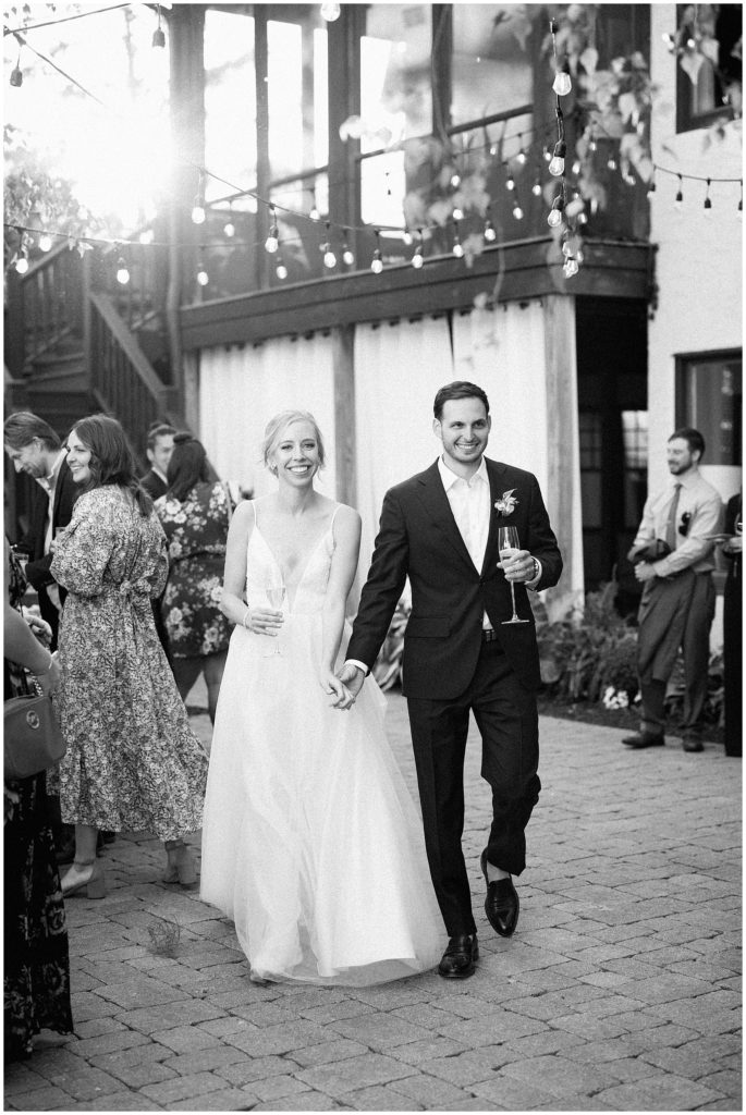Black and white image of couple entering their outdoor reception at Minnesota estate backyard