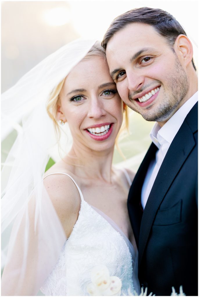 Couple smiles under veil for upscale classic portrait with a fun twist from The Byes Photo